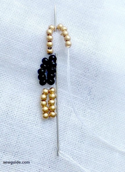 the bead chain is anchored on the fabric with a chain stitch.,