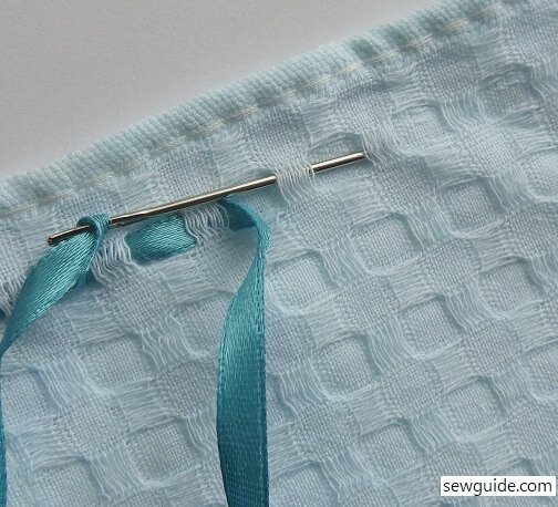 Weave the needle with the ribbon through the thread on the fabric