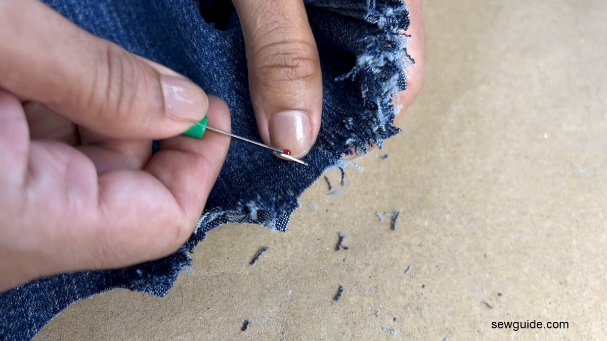 fraying a jeans hem with a seam ripper.