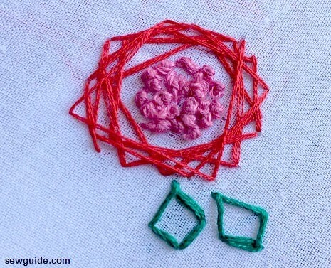 A modern rose made with straight stitches and french knots in the middle