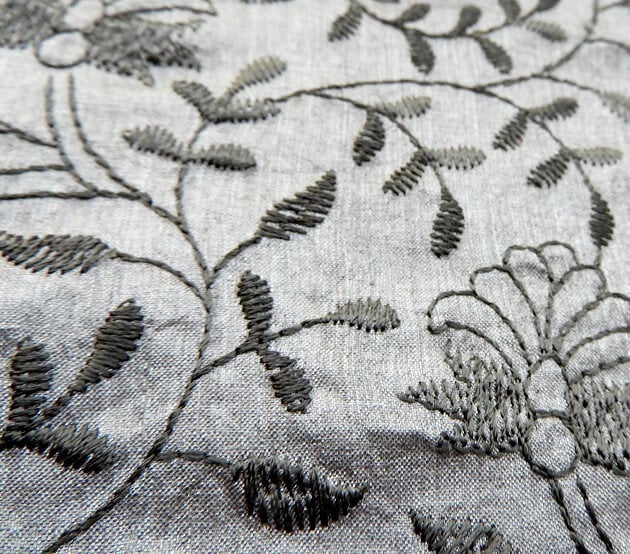 Embroidered fabric with black thread on grey fabric